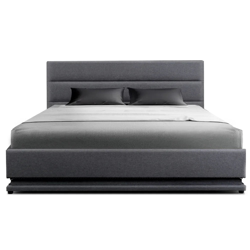 Modern gray upholstered bed with padded headboard and two black pillows on white sheets