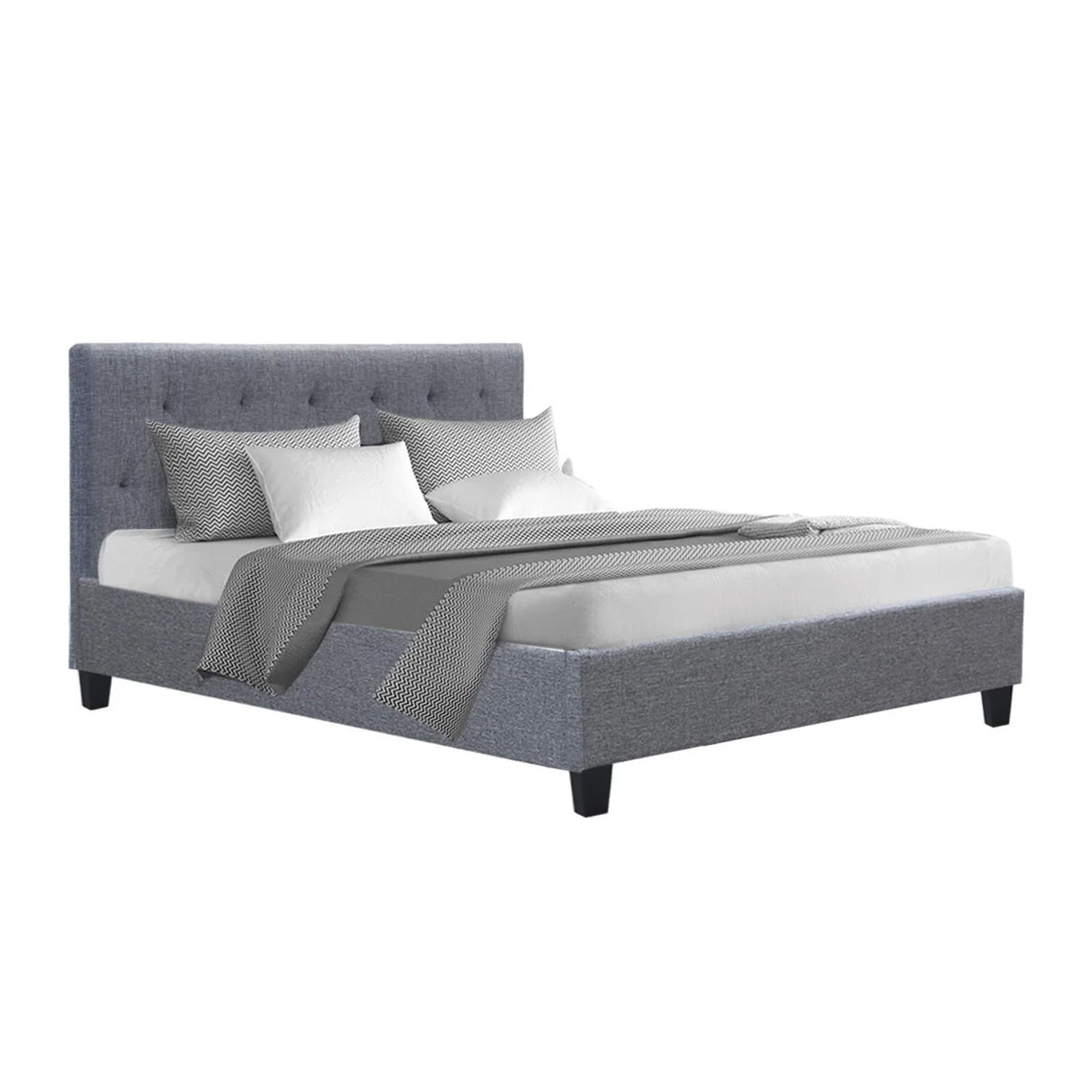 Grey upholstered bed with tufted headboard, white mattress, and patterned pillows and blanket