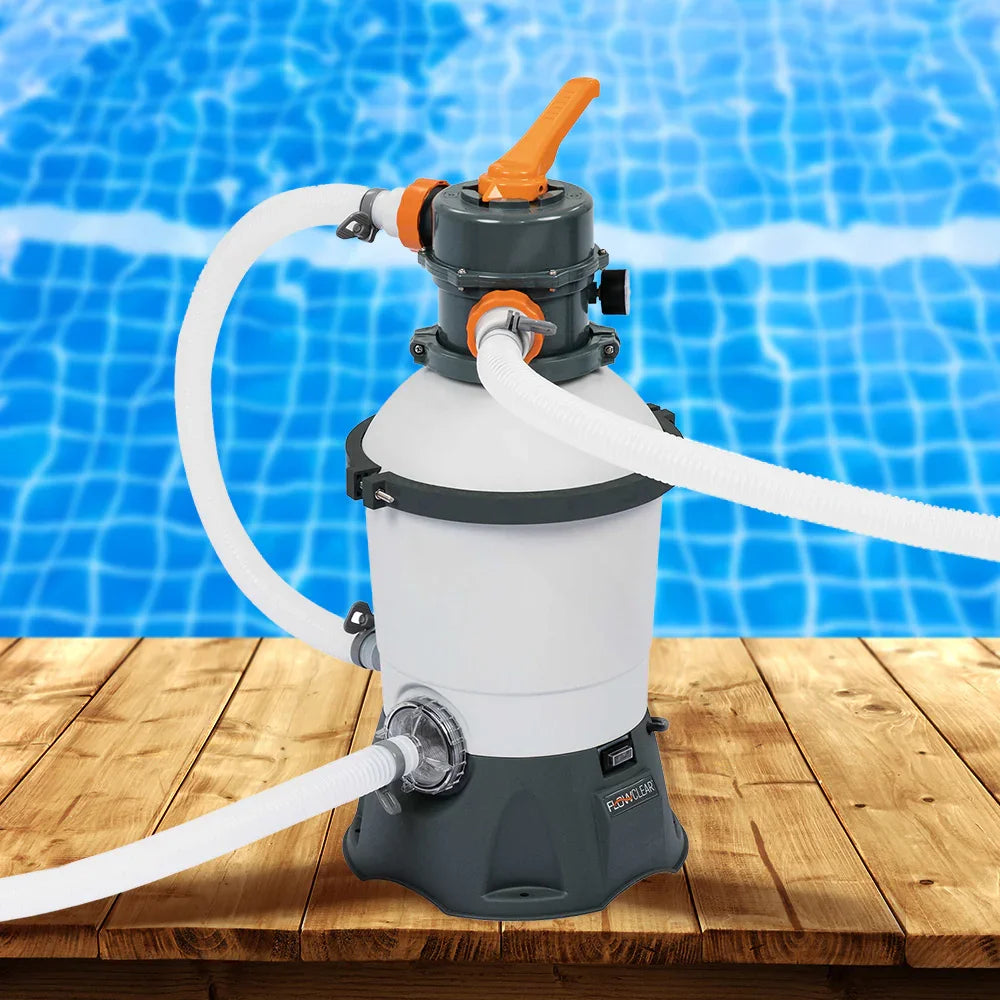 Above ground pool sand filter pump with hoses on wooden deck near blue pool water