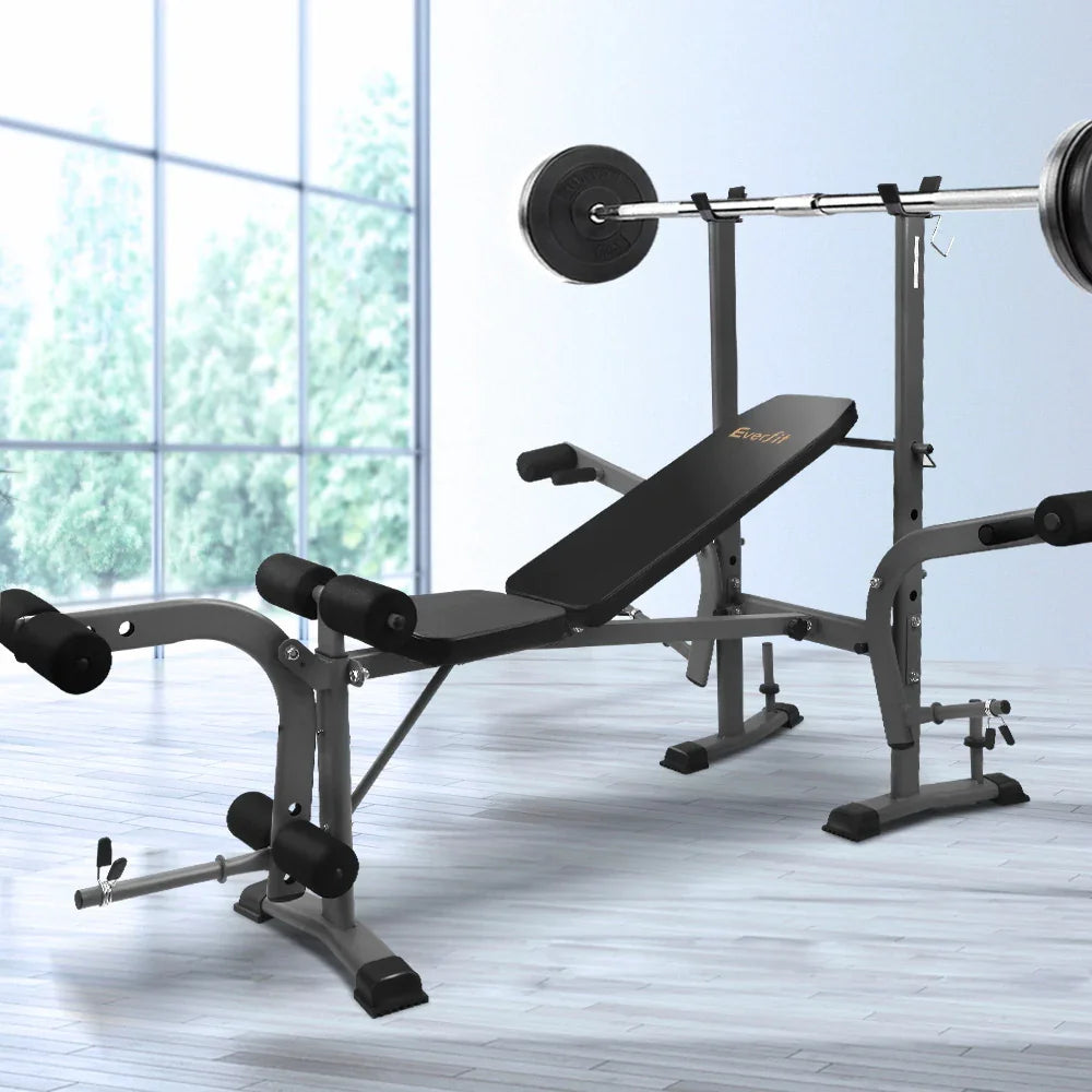 Adjustable weight bench with barbell and leg curl attachments in a bright home gym