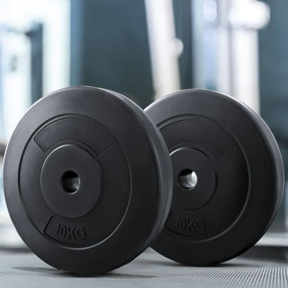Pair of black 10kg weight plates on gym floor with blurred equipment background