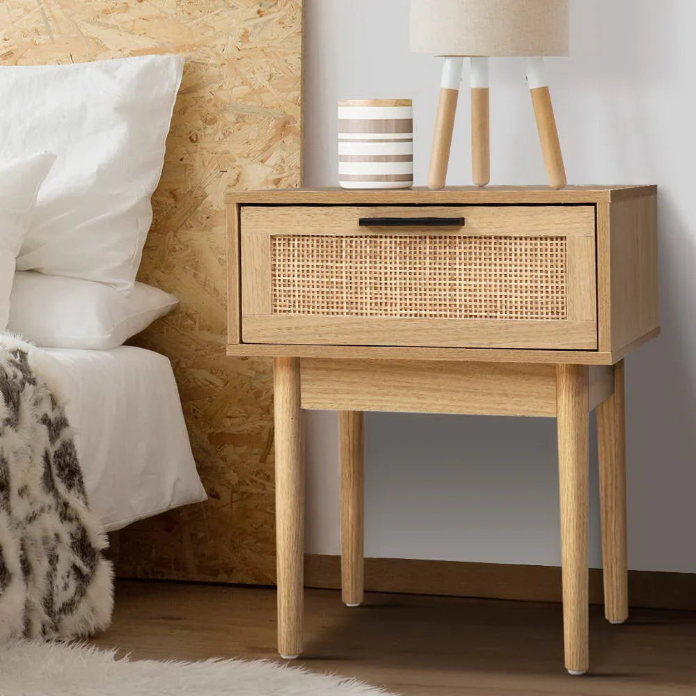 Modern wooden nightstand with rattan drawer, lamp, and dΓ©cor in a cozy bedroom setting