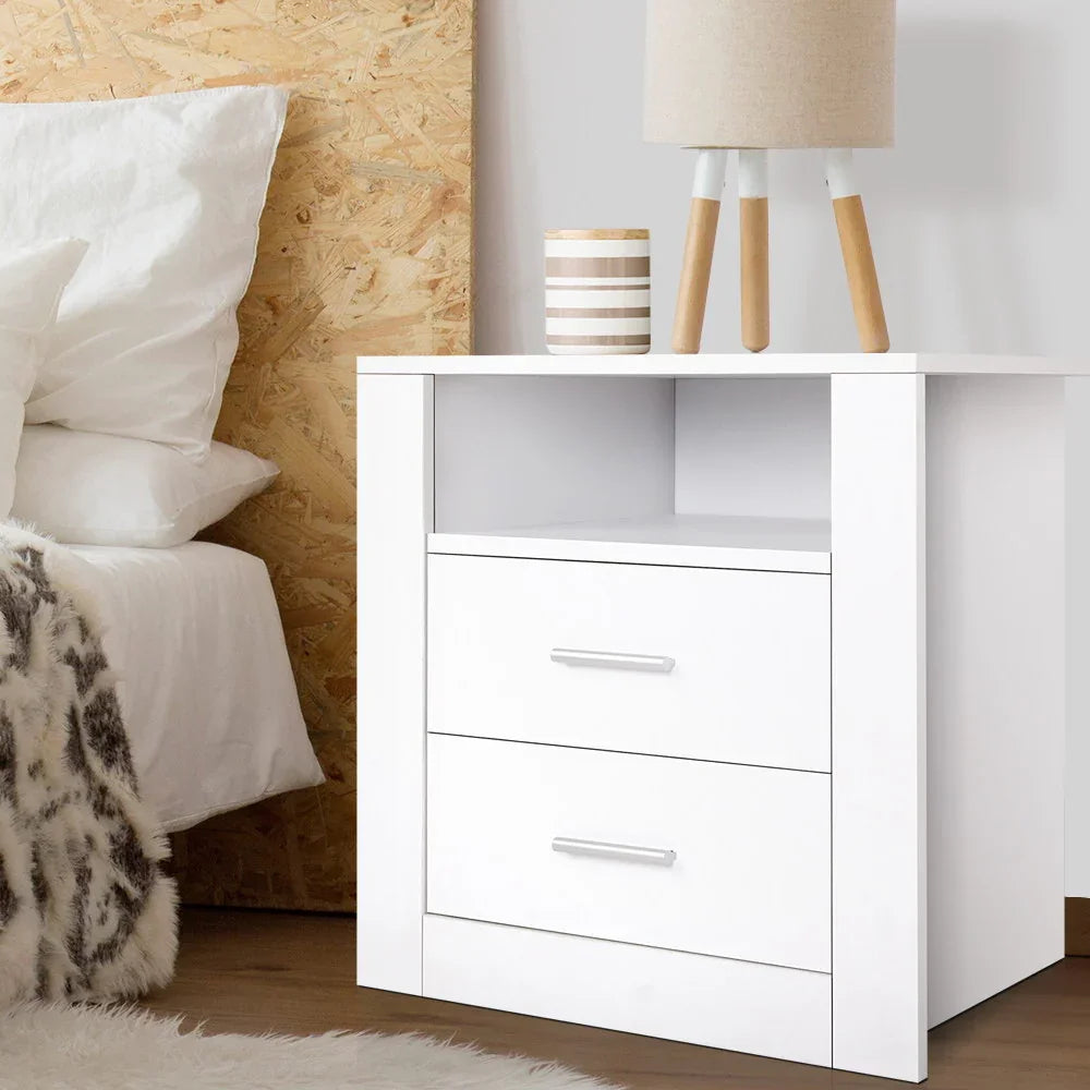 Modern white bedside table with two drawers, open shelf, lamp, and cup in a bedroom