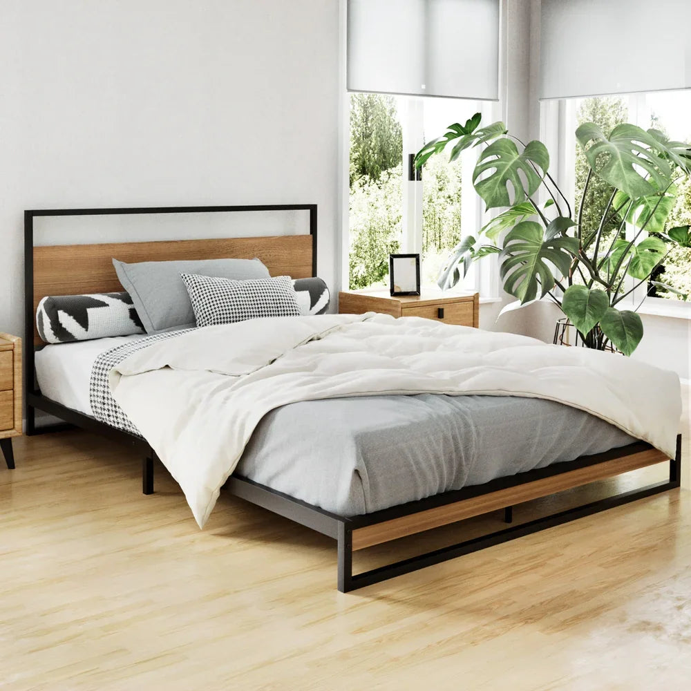 Modern bedroom with wooden and black metal frame bed, neutral bedding, and large green plant by windows
