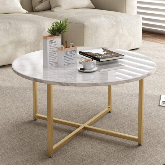 Modern round marble coffee table with gold metal legs in living room, books and coffee cup on top