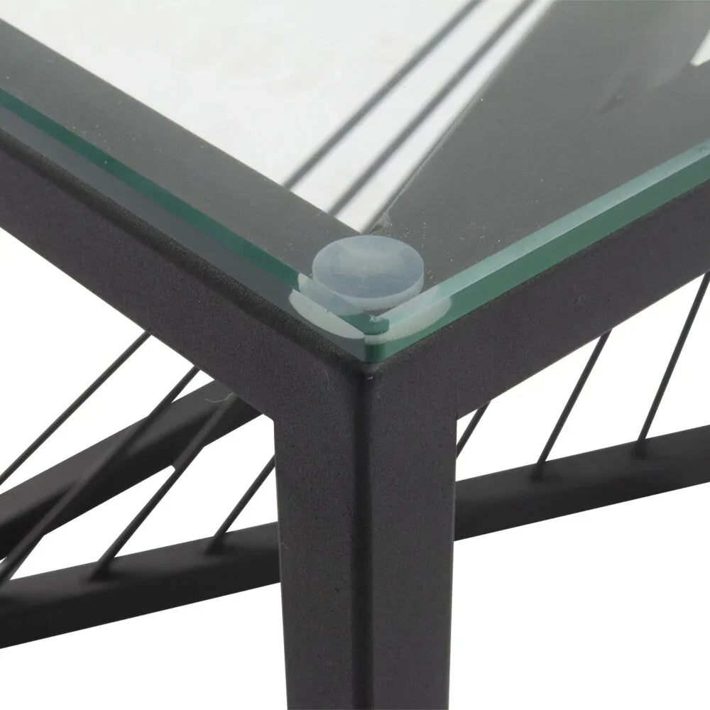 Black metal table corner with clear glass top and support cables, modern furniture detail