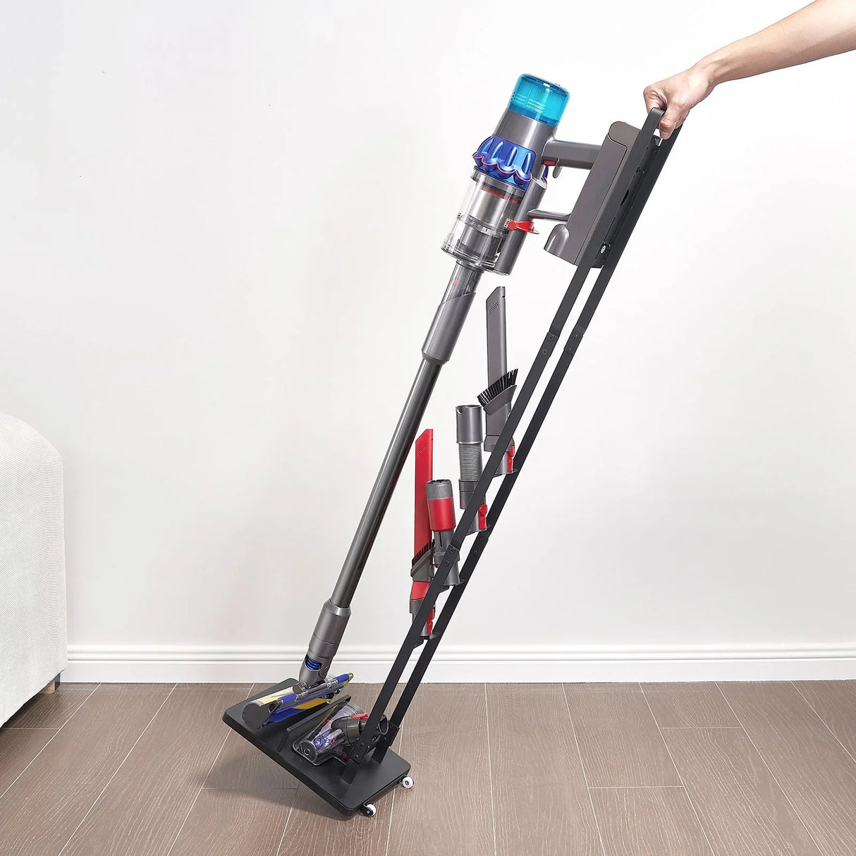 Cordless vacuum cleaner with multiple attachments on a black rolling stand indoors