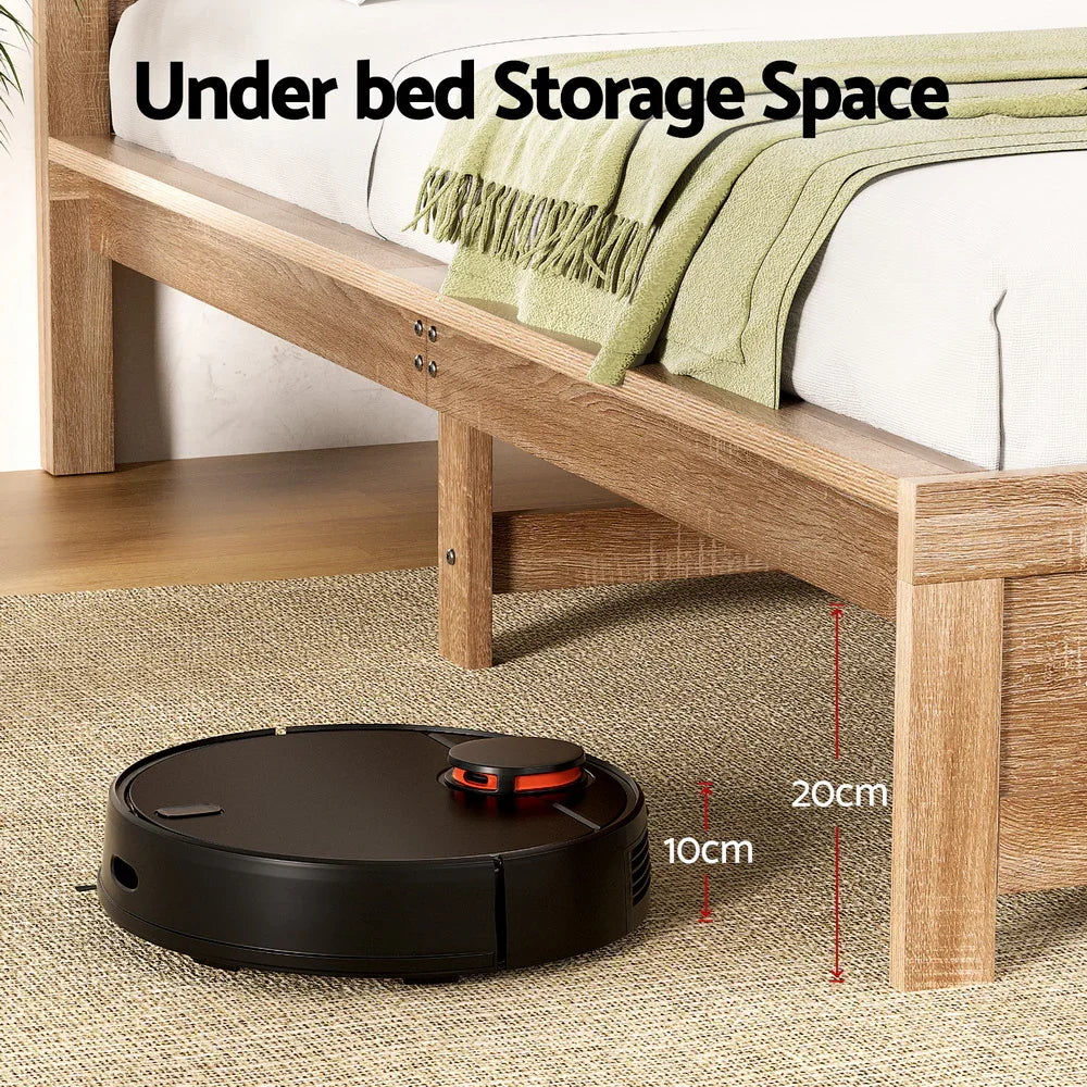 Black robot vacuum cleaning under wooden bed with green blanket, showing 10cm height under vacuum 20cm under bed