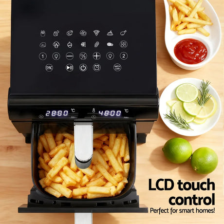 Black air fryer with LCD touch screen, fries in basket, sliced lemons, and dipping sauce