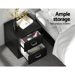 Black bedside table with two open drawers, showing storage dimensions beside a bed
