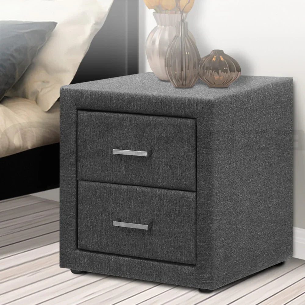 Modern grey fabric nightstand with two drawers, metal handles, and decorative vases