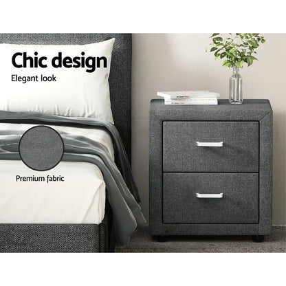 Gray fabric nightstand with two drawers beside a bed, books and plant on top, premium fabric