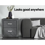 Modern grey nightstand with decorative vases beside a grey sofa and pillow in a minimalist room