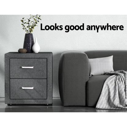 Modern grey nightstand with decorative vases beside a grey sofa and pillow in a minimalist room