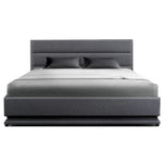 Modern gray upholstered bed with padded headboard and two black pillows on white sheets