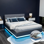 Modern gray fabric bed with blue LED lighting, blue pillows, white blanket, and nightstands in dark bedroom