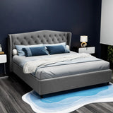 Modern gray upholstered bed with tufted headboard, blue and white bedding, and a blue area rug