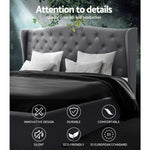 Gray tufted upholstered headboard bed with white pillows and black bedding in nature-inspired setting