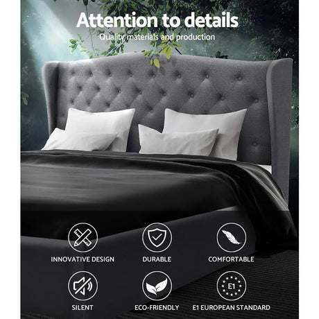 Gray tufted upholstered headboard bed with white pillows and black bedding in nature-inspired setting