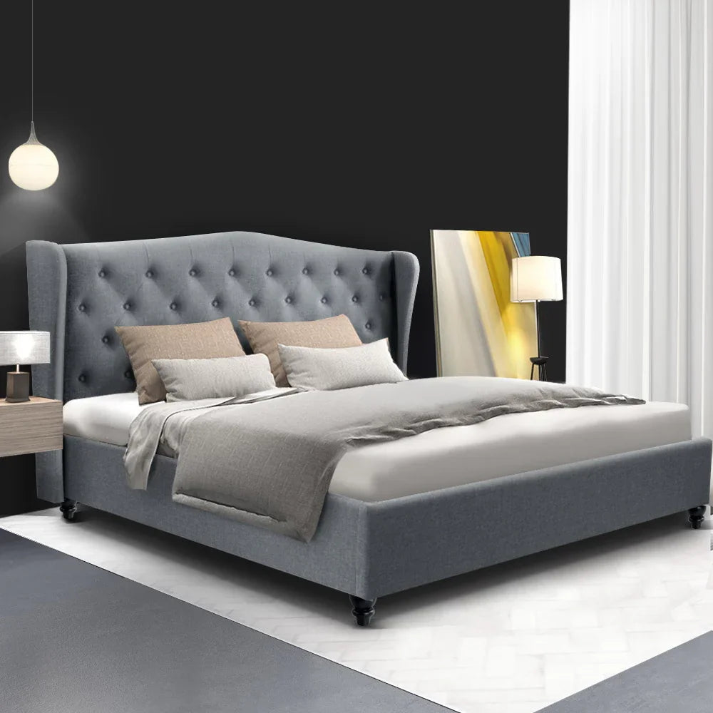Modern bedroom with grey upholstered tufted bed, soft pillows, grey bedding, and minimalist lamps