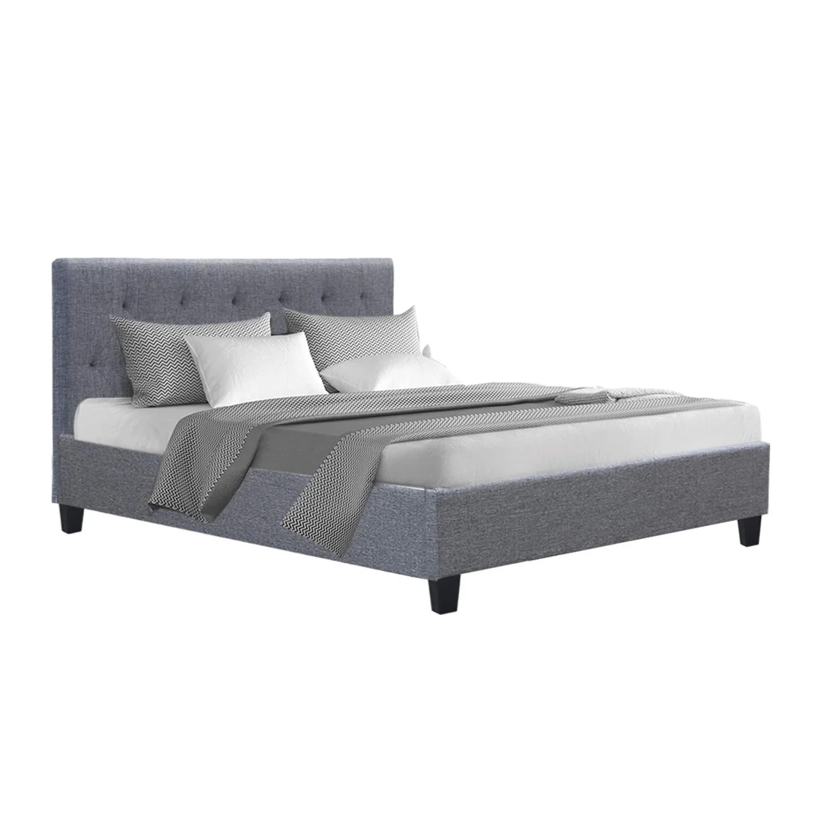 Grey upholstered bed with tufted headboard, white mattress, and patterned pillows and blanket