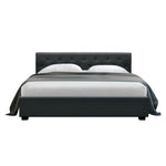 Modern dark gray upholstered bed with tufted headboard and white bedding on white background