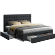 Modern dark gray upholstered bed with tufted headboard and under-bed storage drawers filled with clothes