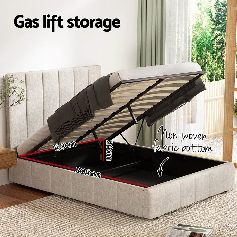 Beige upholstered gas lift storage bed with lifted mattress showing black non-woven fabric storage space