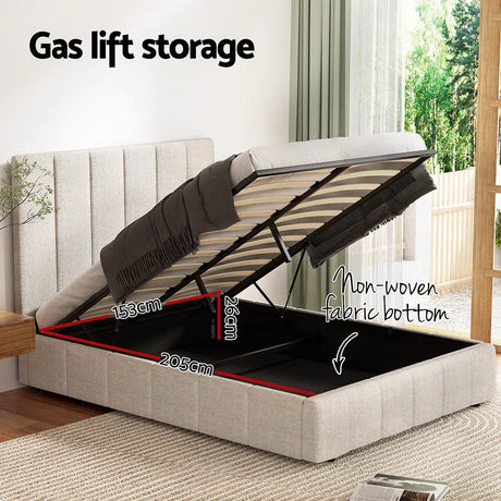 Beige upholstered gas lift storage bed with lifted mattress showing black non-woven fabric storage space