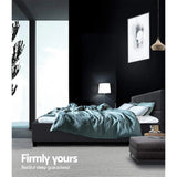 Modern bedroom with dark walls, grey upholstered bed, teal bedding, and ambient lighting