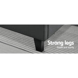 Close-up of black couch leg on striped gray rug highlighting strong, sturdy furniture support