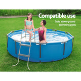 Mother and daughter in swimsuits using blue round above-ground swimming pool with ladder on green lawn