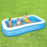 Three children playing and relaxing in a blue and white inflatable pool on green grass