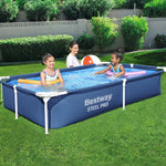 Three children playing in a Bestway Steel Pro above ground pool in a green backyard with a beach ball