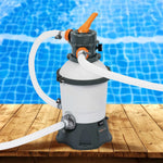 Above ground pool sand filter pump with hoses on wooden deck near blue pool water