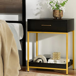 Modern black and gold nightstand with drawer, decorative vase, and books in a cozy bedroom