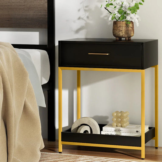 Modern black and gold nightstand with drawer, decorative vase, and books in a cozy bedroom