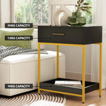 Modern black and gold side table with labeled weight capacities, by sofa and window.