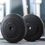 Pair of black 10kg weight plates on gym floor with blurred fitness equipment background