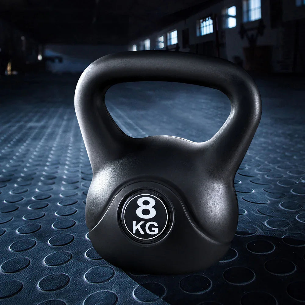 8 kg black kettlebell on textured gym floor in dimly lit fitness studio