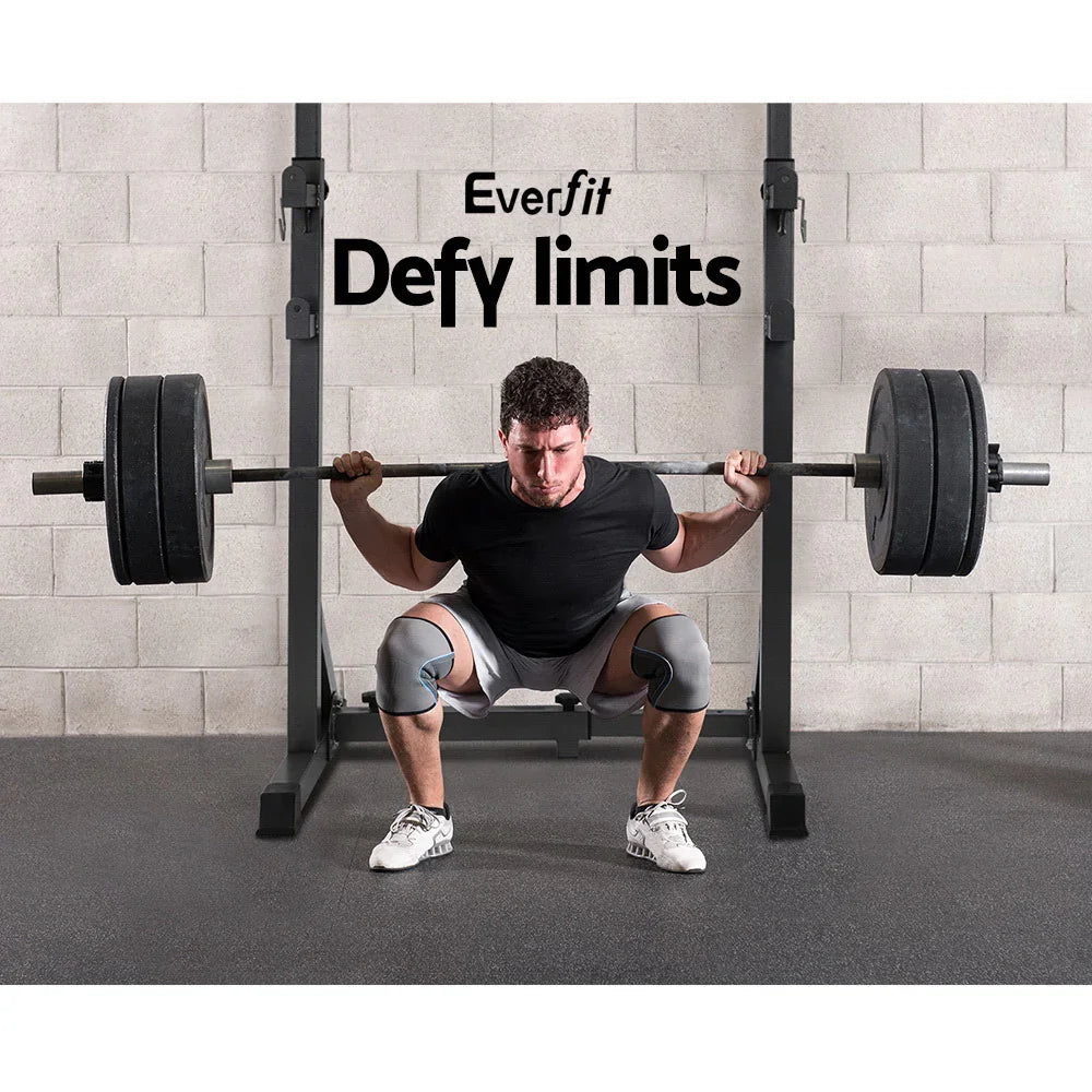 Man lifting barbell on squat rack in gym with Everfit Defy limits slogan on wall