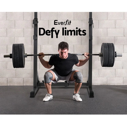 Man lifting barbell on squat rack in gym with Everfit Defy limits slogan on wall
