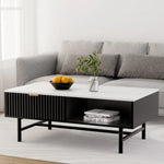 Modern black and white coffee table with decorative bowl, plant, books, and grey sofa