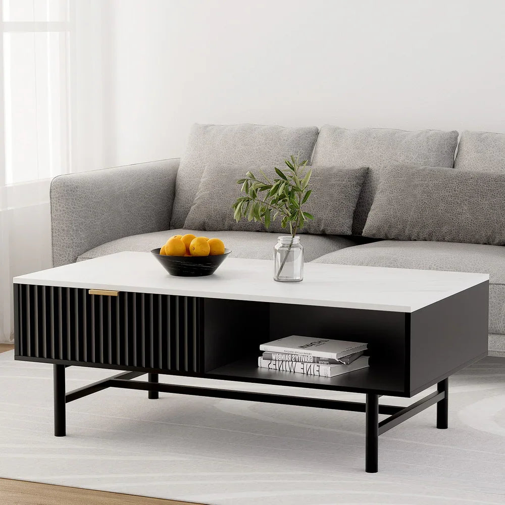 Modern black and white coffee table with decorative bowl, plant, books, and grey sofa