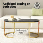 Black marble oval coffee table with gold powder-coated metal legs in modern living room.