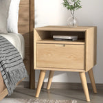 Modern light wood nightstand with open shelf, drawer, books, and glass vase in bedroom