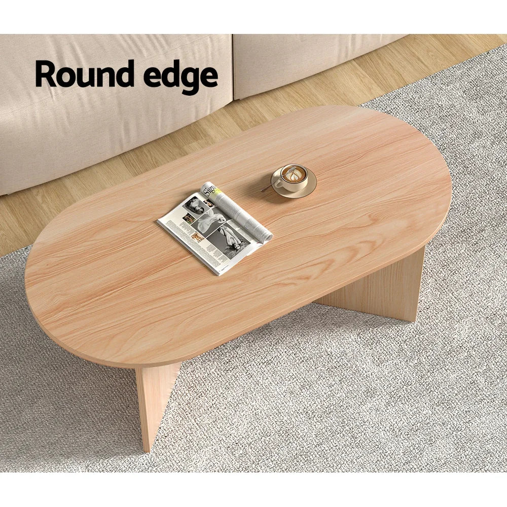 Oval wood coffee table with round edge, on grey rug, magazine and cup on top