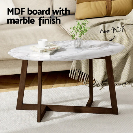 Oval MDF coffee table with marble finish, dark wood legs, in a modern living room setting.