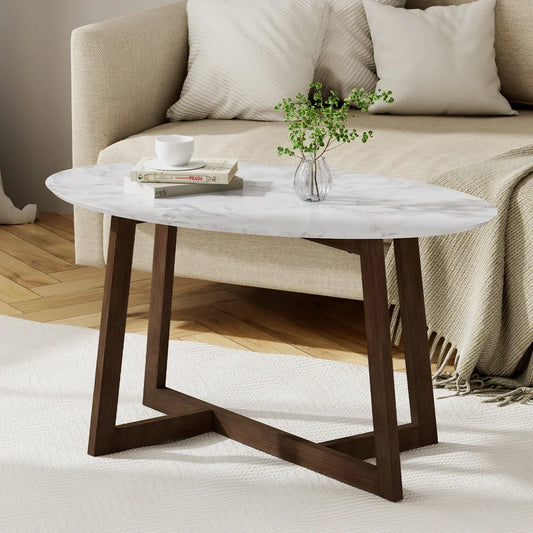 Modern oval coffee table with white marble top and wood base in a cozy living room setting