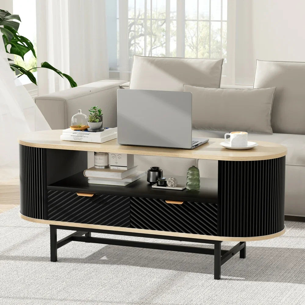 Modern oval coffee table with laptop, books and decor in a bright living room